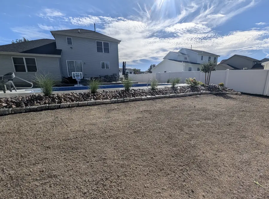 The same backyard graded smooth with a river rock bed, block edging and ornamental grasses